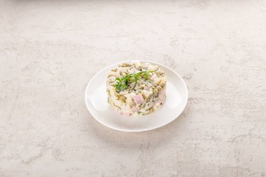 Beyaz tabakta tavuklu Olivier salatası.