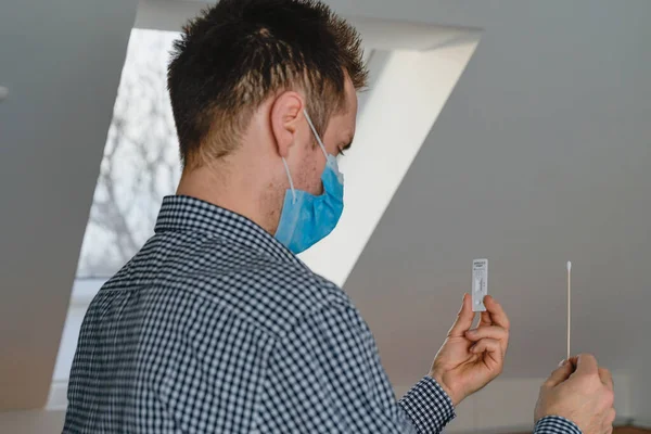 man does rapid self test for COVID-19 home test kit. Coronavirus nasal swab test for infection, pcr rapid test. health check with a cotton swab and a test cassette.