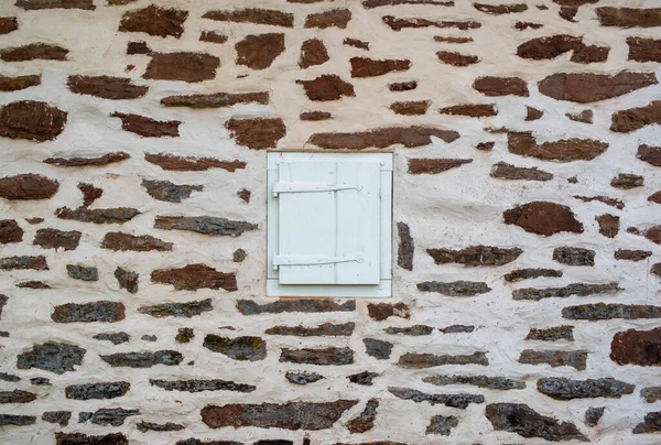 Taş duvarda ahşap panjurlu beyaz bir pencere. — Stok fotoğraf