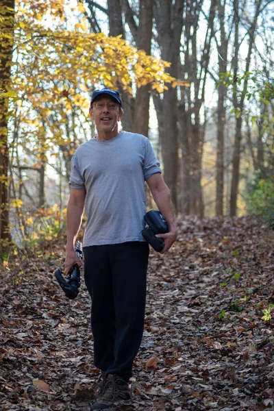 Hombre caucásico caminando en el bosque de otoño llevando un trípode — Foto de Stock