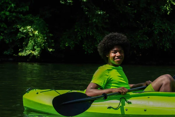Happy teenager kayaking with paddle on scenic river with copy space — Stock Photo, Image