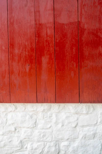 Vertical bright red wood and whitewashed stone exterior wall close up.