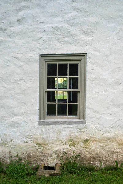 Kolonialsteinhaus blickt in blaues Zwölfscheibenfenster — Stockfoto