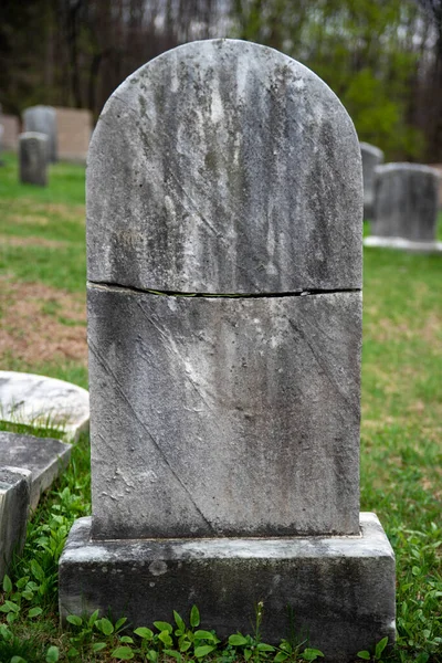 Grafsteen grafsteen doormidden gekraakt op groen grasveld. — Stockfoto