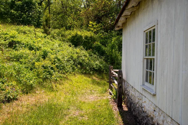 Зеленая трава вокруг колониального белоснежного дома с антикварным окном — стоковое фото