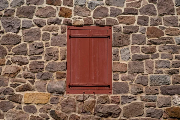 Etrafı taş duvarlarla çevrili kapalı kırmızı antika pencere panjurları. — Stok fotoğraf