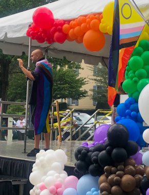 Okuma, PA / USA - 08 / 22 / 2021 Editör sadece. Teğmen. Vali John Fetterman, Onur Süreci bayrağı takıyor. Gurur Festivali 'nde gökkuşağı balonları ile sahnede konuşuyor..