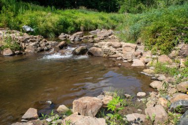 Akan nehirdeki su, eski bir koloni taşı barajının yıkıntılarının üzerine dökülüyor.