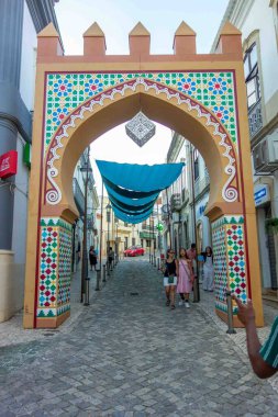 Silves, Portekiz 08-12-2025 Dekoratif Mağribi kemeri kaldırım taşları üzerinde gölgelik tentelerle örtülü turistlerin arabaları ve ortaçağ Algarve büyüleyici şehir seyahatlerinde vitrinler