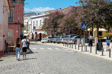 Silves, Portekiz, 04-22-2025,... genç bir çift, ortaçağ ortaçağ Algarve şehrinde,... alışveriş merkezleri ve park yerleriyle el ele yürüyorlar.