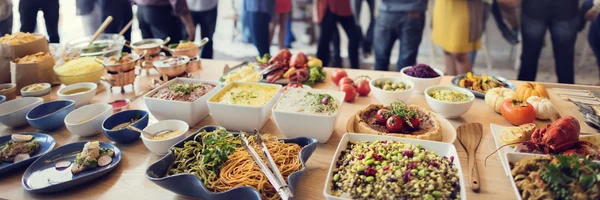 Amigos com diferentes alimentos e bebidas — Fotografia de Stock