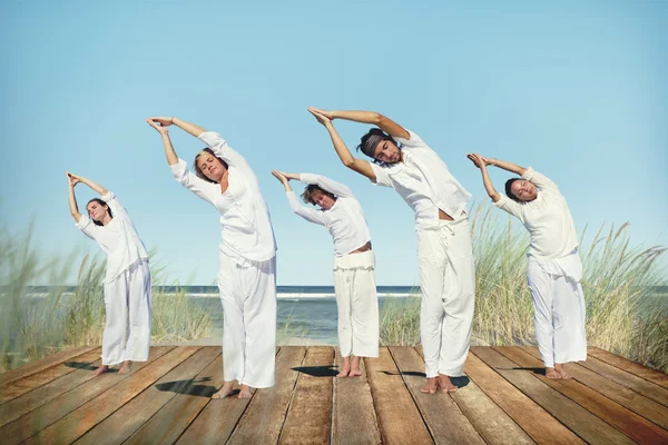 Människor som utför yoga på stranden — Stockfoto