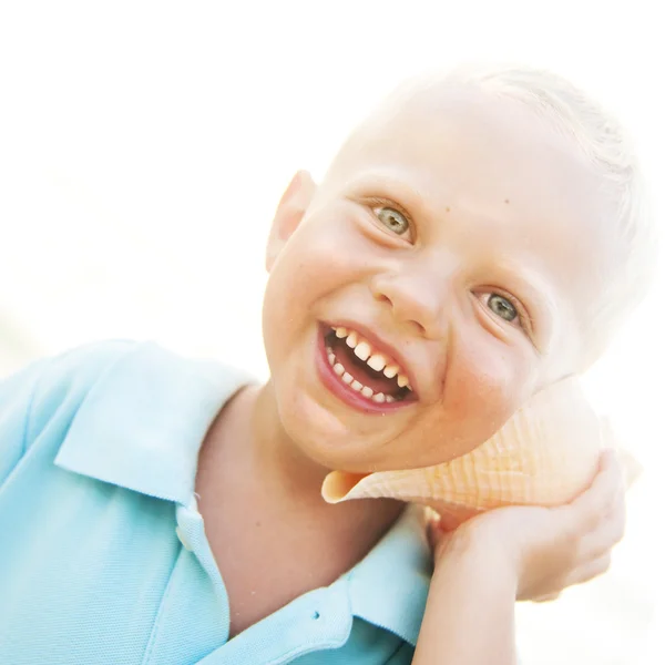 Niño pequeño escuchando concha marina — Foto de Stock