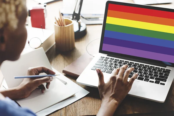 Vrouw die op laptop met regenboog werkt — Stockfoto