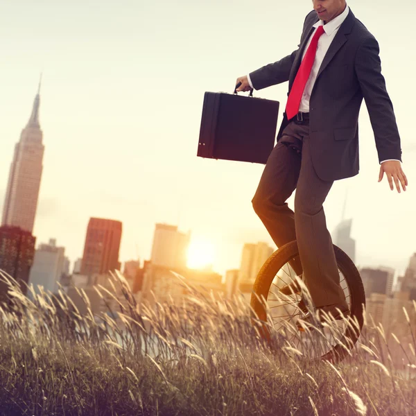 Businessman riding one wheel bicycle — Stock Photo, Image