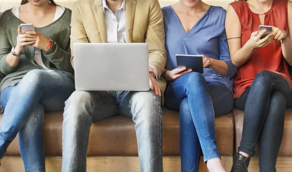 Menschen sitzen mit digitalen Geräten — Stockfoto