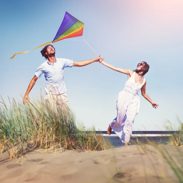 Alegre pareja jugando cometa por la playa — Foto de Stock