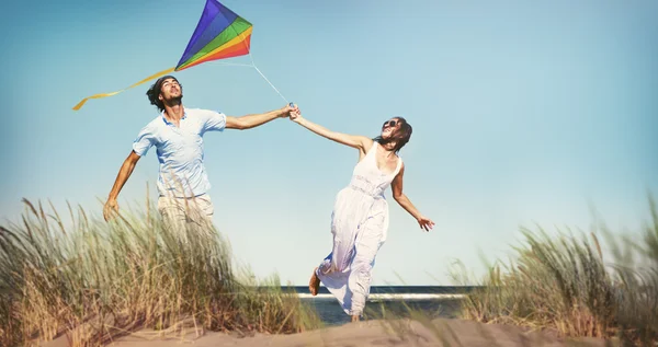 Alegre pareja jugando cometa por la playa — Foto de Stock