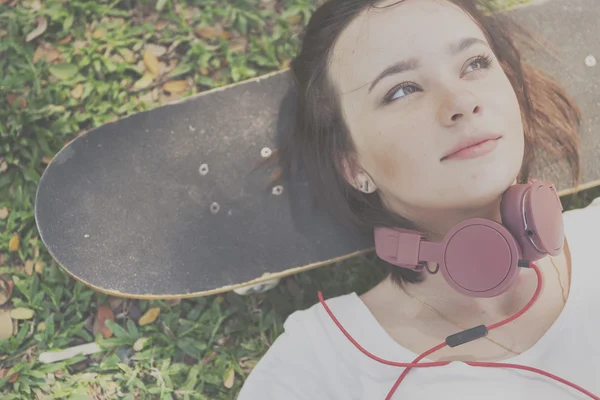 Mulher com fones de ouvido está no skate — Fotografia de Stock