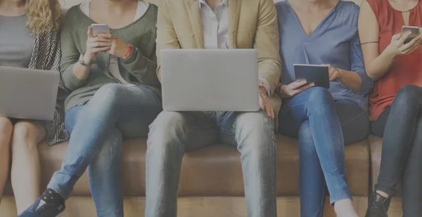 Menschen sitzen mit verschiedenen digitalen Geräten — Stockfoto