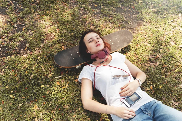 Donna con cuffie si trova sullo skateboard — Foto Stock