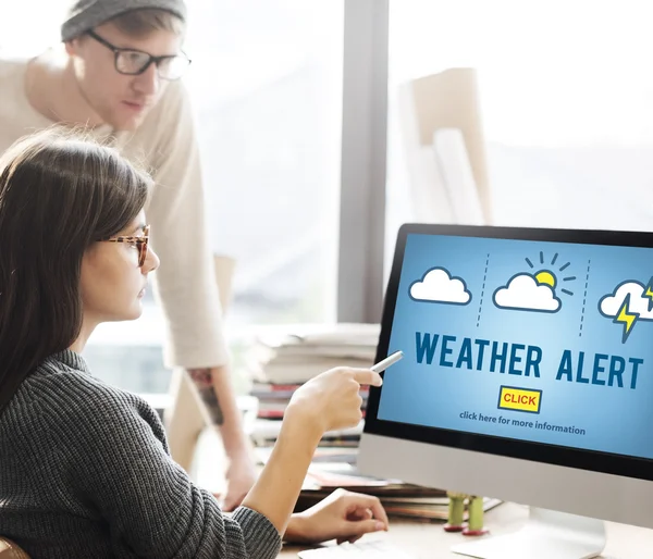 Frau zeigt auf Monitor mit Wetterwarnung — Stockfoto