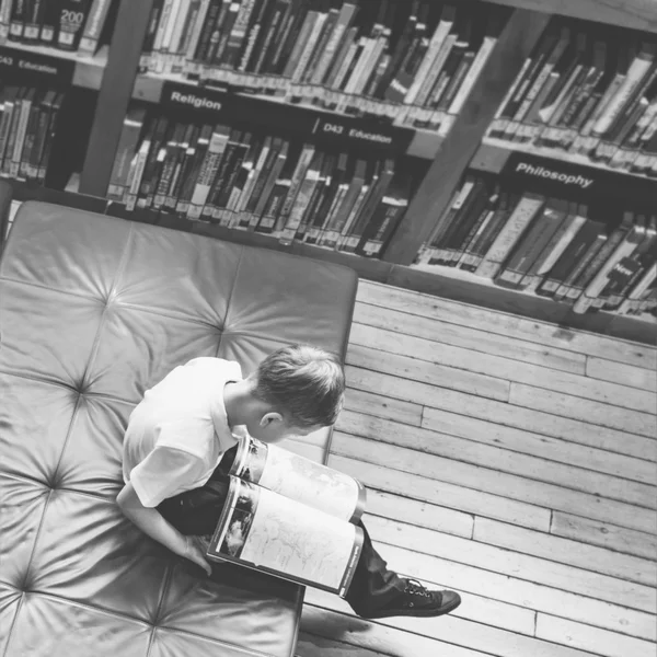 Jongen lezen boek in de bibliotheek — Stockfoto