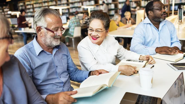 Mature people studying in library — Stock Photo, Image