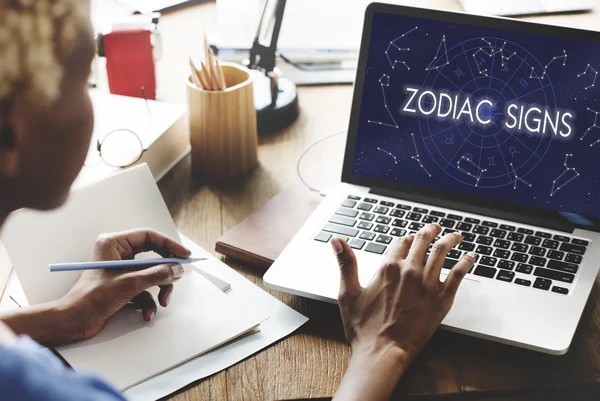 Kobieta pracuje na laptopie z znaków zodiaku — Zdjęcie stockowe