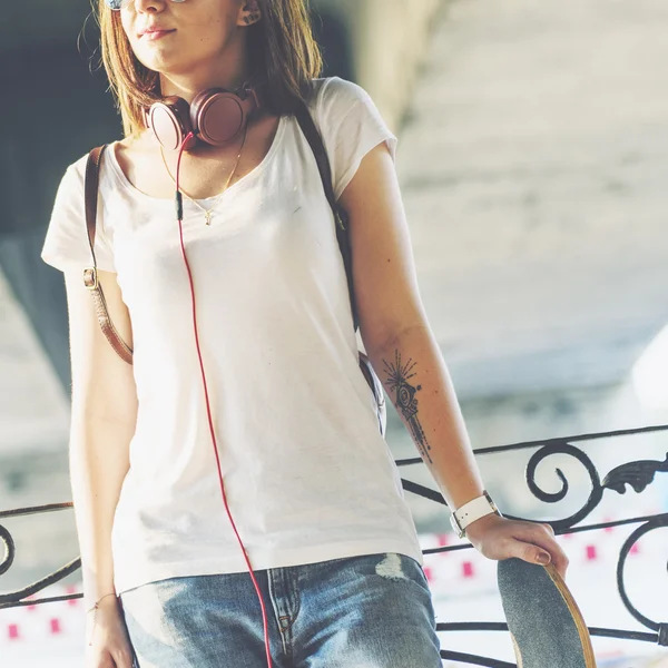 Mulher com skate e fones de ouvido — Fotografia de Stock