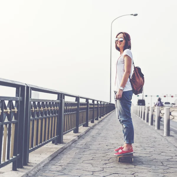 Femme avec skateboard et écouteurs — Photo