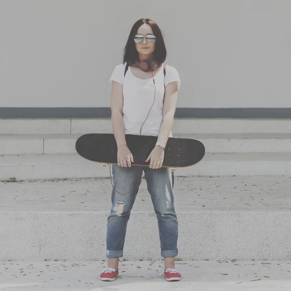 Donna con skateboard e cuffie — Foto Stock