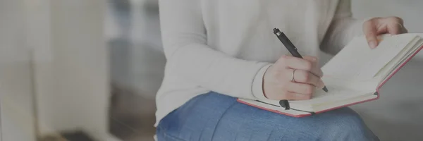 Frau schreibt in Notizbuch — Stockfoto