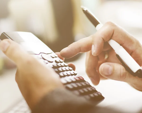 Businessman considers on calculator — Stock Photo, Image