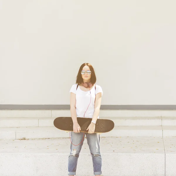 Kvinna med skateboard och hörlurar — Stockfoto