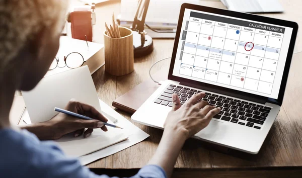 Mulher trabalhando no laptop com calendário — Fotografia de Stock