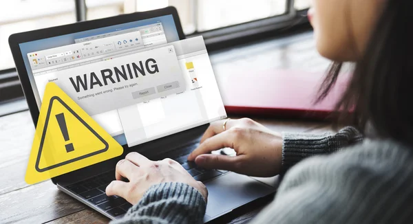 Woman typing on laptop with warning — Stock Photo, Image