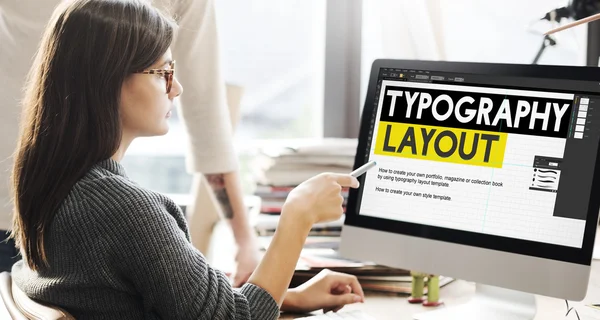 Frau zeigt auf Monitor mit Typografie-Layout — Stockfoto
