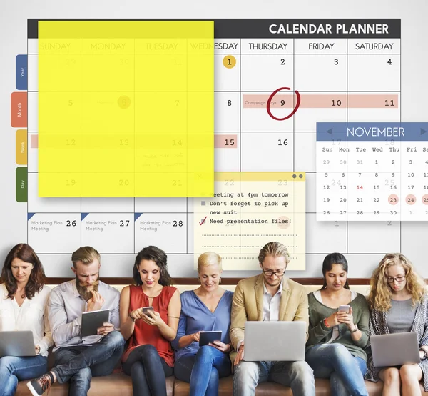 Persone si siedono con dispositivi e calendario — Foto Stock