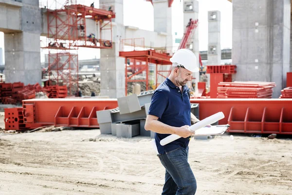 Bouw werknemer onderzoekt tekeningen — Stockfoto