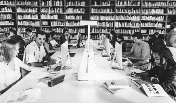 Estudantes usando computadores na biblioteca universitária — Fotografia de Stock