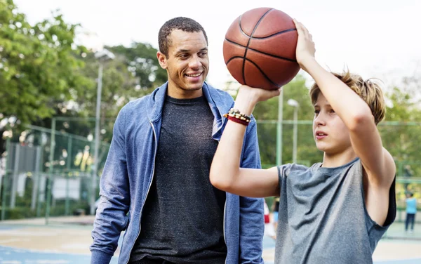 Esportista ensinando menino jogar basquete — Fotografia de Stock