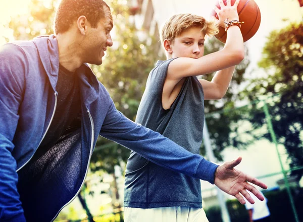 Esportista ensinando menino jogar basquete — Fotografia de Stock