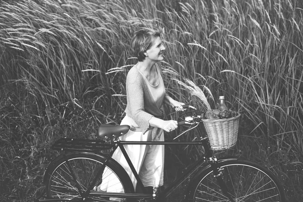 Mulher com bicicleta no campo — Fotografia de Stock