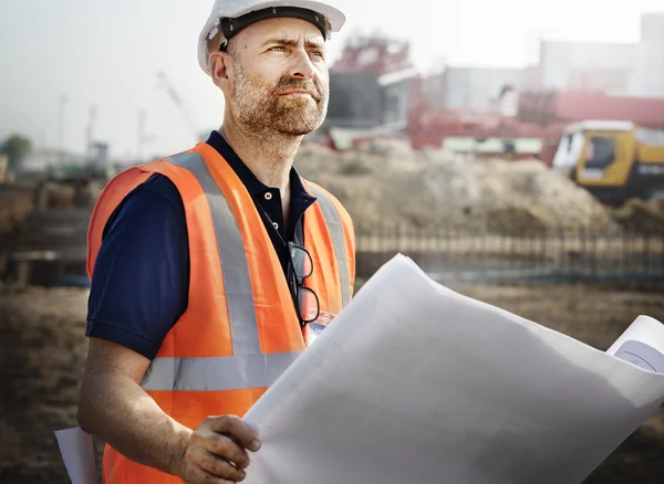 Budowy pracownik patrząc na plan budynku — Zdjęcie stockowe