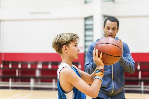 Sportsman teaching boy play Basketball