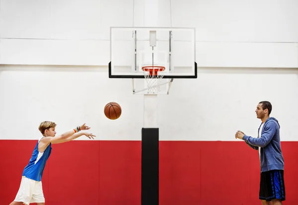 Sportman onderwijzen van jongen spelen basketbal — Stockfoto