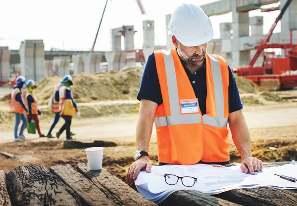 Trabalhador da construção Olhando para o plano de construção — Fotografia de Stock