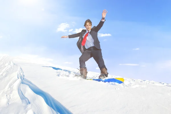 Businessman snowboarding on mountain — Stock Photo, Image