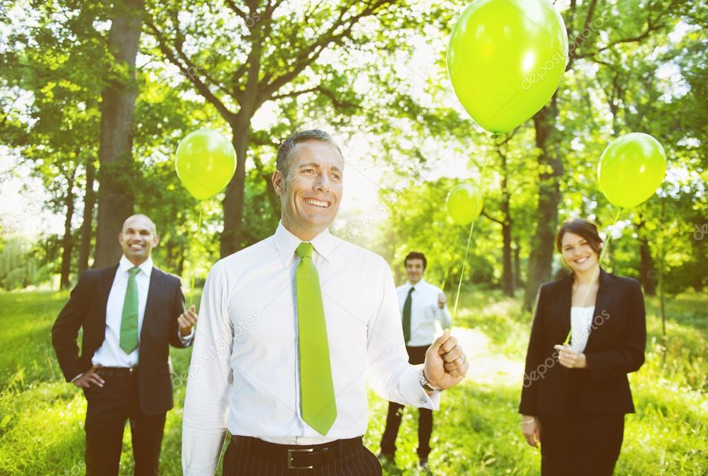 people outdoors holding green balloons